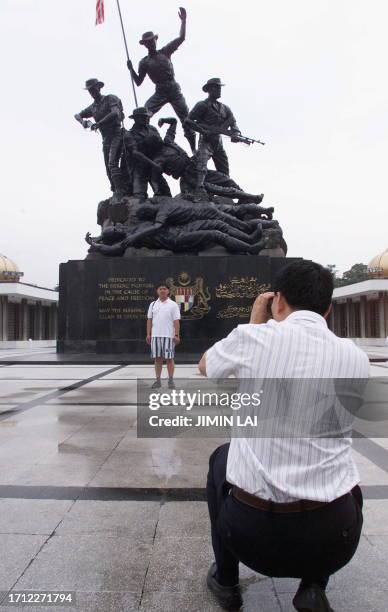 Tourist takes a picture of his friend in front of Malaysia's National Monument 28 June 1999 in Kuala Lumpur. Malaysian Prime Minister Mahathir...