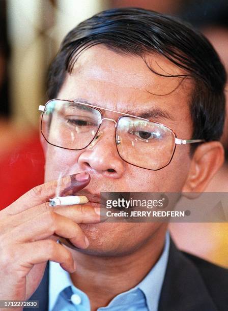 Cambodian co-Prime Minister and strongman Hun Sen smokes, with his index finger blackened by indelible ink showing he cast his vote in the election...