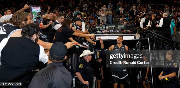 Victor Wembanyama of the San Antonio Spurs greets fans as he enters the court during the San Antonio Spurs Silver and Black Scrimmage at Frost Bank...