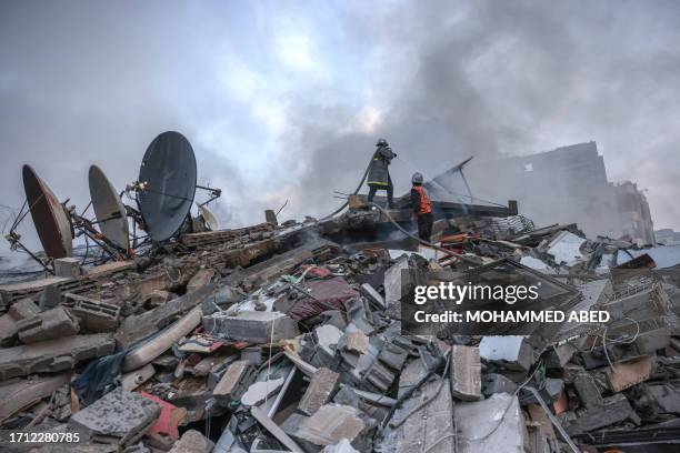 Palestinian firemen extinguish a fire that was raging in a residential building destroyed by Israeli airstrikes in Gaza City on October 8, 2023....