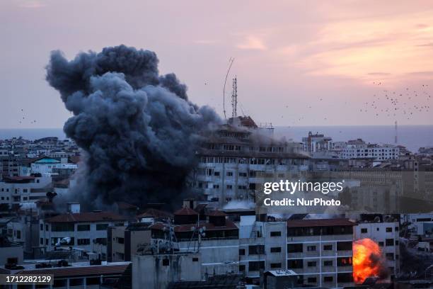 Smoke rises and ball of fire over a buildings in Gaza City on October 7, 2023 during an Israeli air strike. Medical sources in Gaza say at least 198...