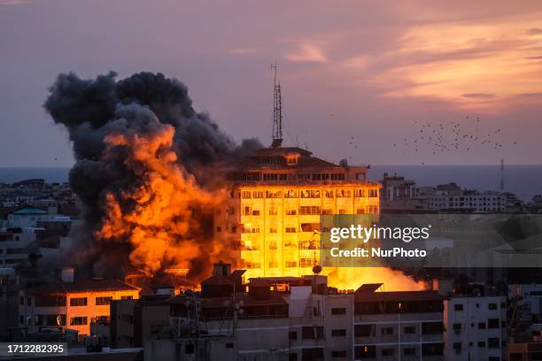 Smoke rises and ball of fire over a buildings in Gaza City on October 7, 2023 during an Israeli air strike. Medical sources in Gaza say at least 198...