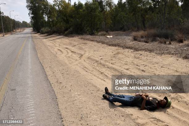 Corpse of a Palestinian militant lies along a road in an undisclosed location on the border with the Gaza Stip on October 8, 2023. At least 40 people...