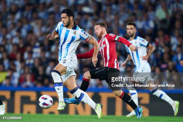 Mikel Merino of Real Sociedad duels for the ball with Iker Muniain of Athletic Club during the LaLiga EA Sports match between Real Sociedad and...