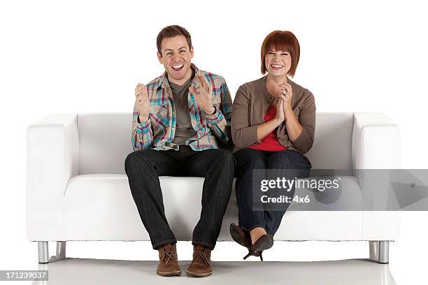 happy couple siting on a couch and clapping - woman sitting on mans lap stockfoto's en -beelden