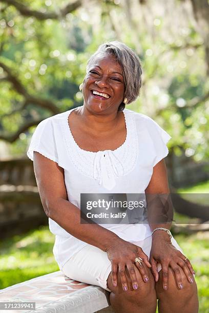 portrait of mature african american woman - hand op knie stockfoto's en -beelden