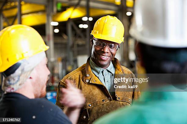 multiétnico de los trabajadores, hablar usando cascos - casco de trabajo fotografías e imágenes de stock