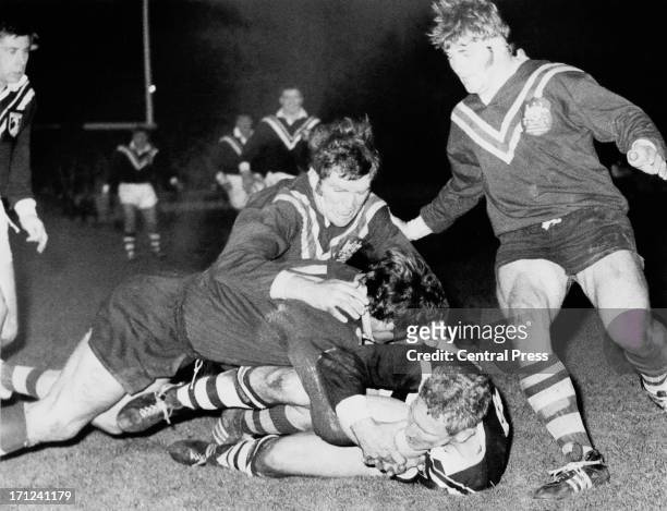 New Zealand front row forward Gary Smith is brought down by Australia's Bob McCarthy and Elwyn Walters during Australia's first match in defence of...