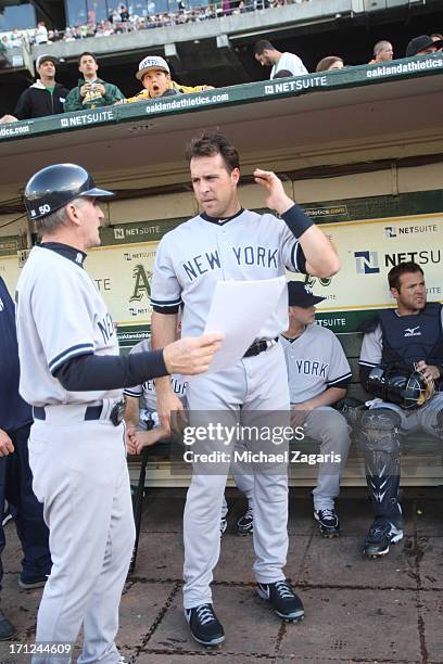 First Base Coach Mick Kelleher of the New York Yankees talks with Mark Teixeira in the dugout prior to the game against the Oakland Athletics at O.co...