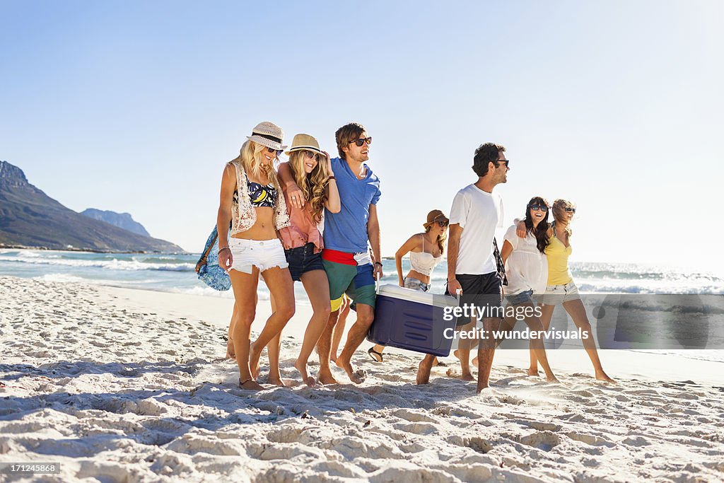 Group of people carrying cooler to party on beach
