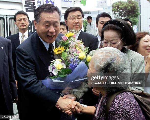 Japanese Prime Minister and ruling Liberal Democratic Party leader Yoshiro Mori , holding a bouquet of flowers, whilst he shakes hands with...