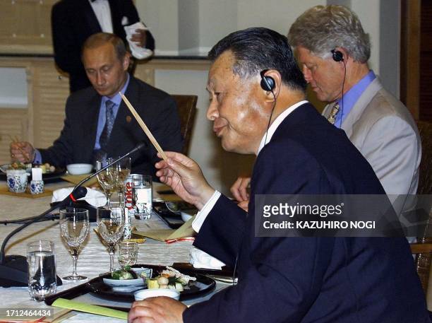Japanese Prime Minister Yoshiro Mori demonstrates the use of chopsticks as Russian President Vladimir Putin and US President Bill Clinton listen...