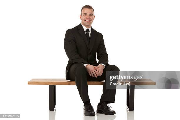 portrait of happy bsusinessman sitting on a bench - dress shoe stock pictures, royalty-free photos & images