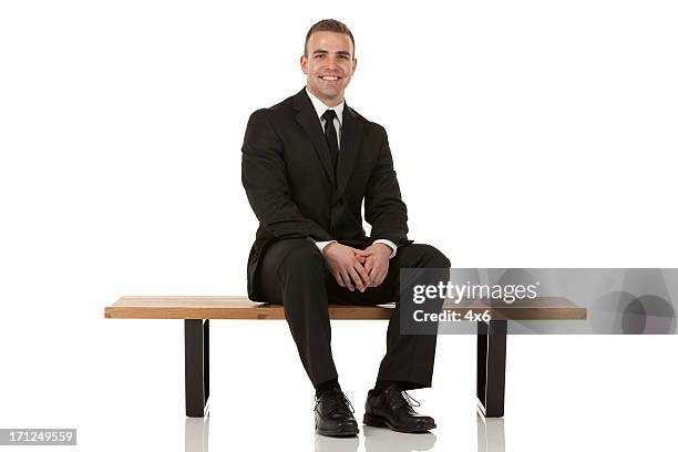 portrait of happy bsusinessman sitting on a bench - sitting bench stock pictures, royalty-free photos & images