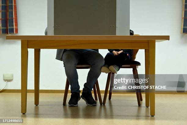 Small child sits next to a voter filling out ballot papers in a voting box at a polling station in Rottenburg an der Laaber, southern Germany, during...