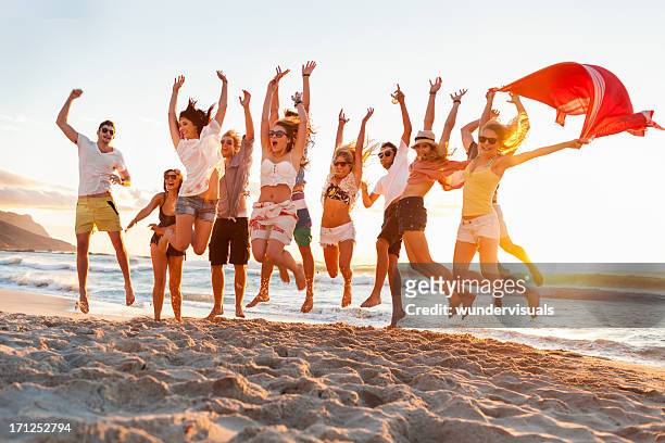 jeunes adultes sauter à l'unisson sur la plage - beach music festival photos et images de collection