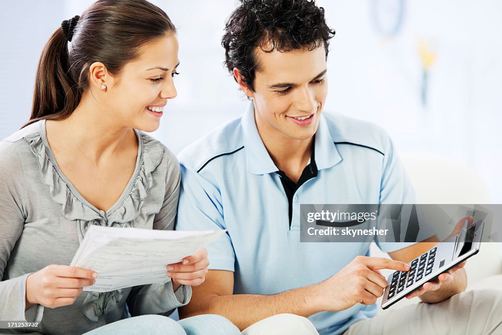 Young cheerful couple doing their taxes.