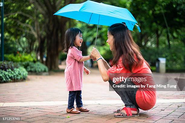 young mom holding an umbrella with toddler girl - adulto de mediana edad fotografías e imágenes de stock