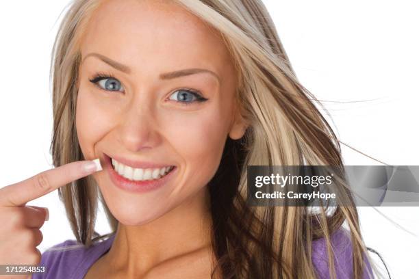 adulto joven señalando en su sonrisa - odontología cosmética fotografías e imágenes de stock