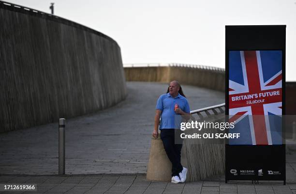 Man stands near a poster for the Labour Party, near their conference venue, on day one of the party's conference in Liverpool, north west England on...