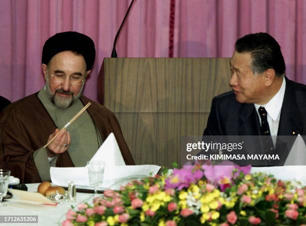 Iranian President Mohammad Khatami tests chopsticks as Japanese Prime Minister Yoshiro Mori looks on at the start of a banquet hosted by the premier...