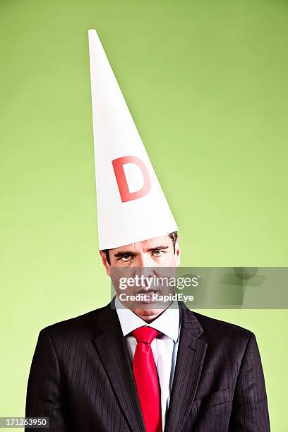 humorous study of businessman looking dumb in dunce cap - dumstrut bildbanksfoton och bilder