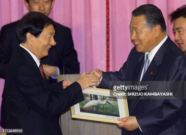 Chinese Premier Zhu Rongji shakes hands with his Japanese counterpart Yoshiro Mori as he hands over to Mori a framed photo of a female crested ibis...