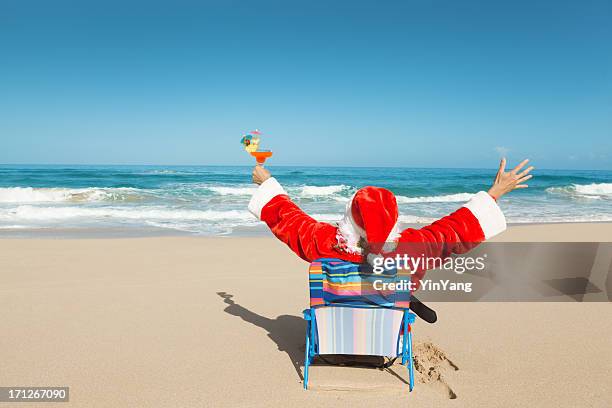 happy christmas santa with drink enjoying hawaiian tropical beach vacation - santa suit stock pictures, royalty-free photos & images