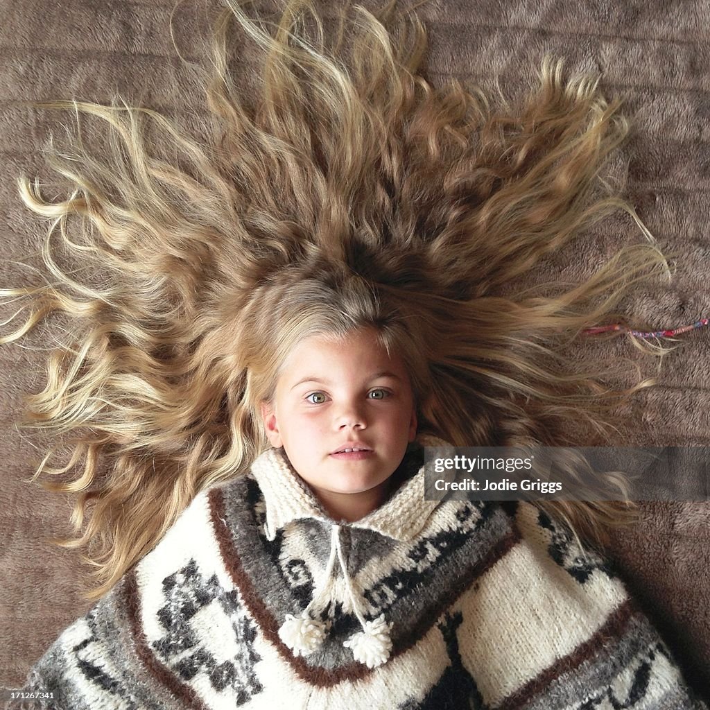 Young child laying on ground surrounded by hair