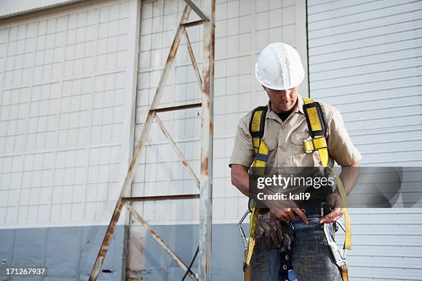 worker putting on safety harness - work glove stock pictures, royalty-free photos & images