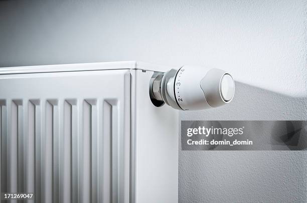modern white radiator with thermostat reduced to economy mode - radiator stock pictures, royalty-free photos & images