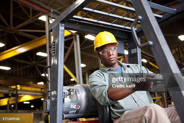 african american worker driving forklift - manufacturing machinery stockfoto's en -beelden