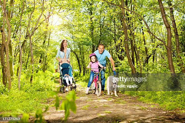 família com dois filhos andar e ciclismo em uma floresta. - two kids with cycle imagens e fotografias de stock