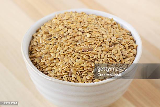 cerámico bowl de lino semillas en mesa de madera - flax seed fotografías e imágenes de stock