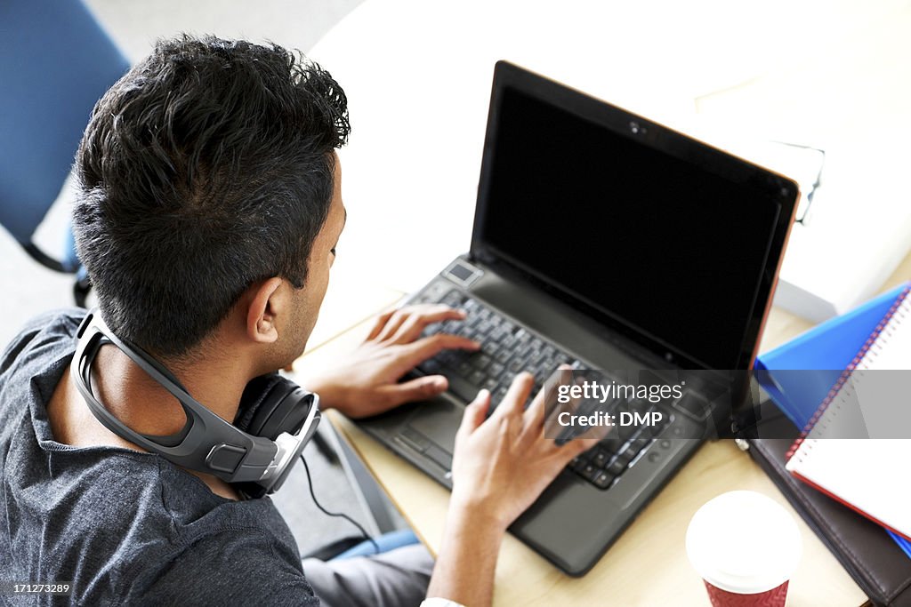 Young Indian student using laptop computer