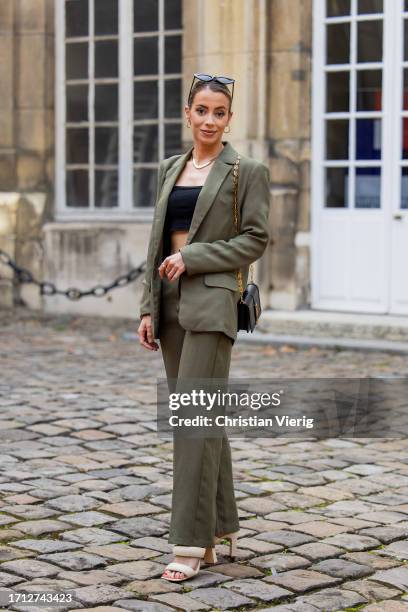 Guest wears black bag, green suit, black cropped top outside RDNT Andre Tan during the Womenswear Spring/Summer 2024 as part of Paris Fashion Week on...