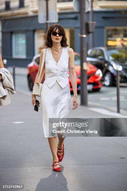 Guest wears white vest, silk skirt, red heels outside RDNT Andre Tan during the Womenswear Spring/Summer 2024 as part of Paris Fashion Week on...