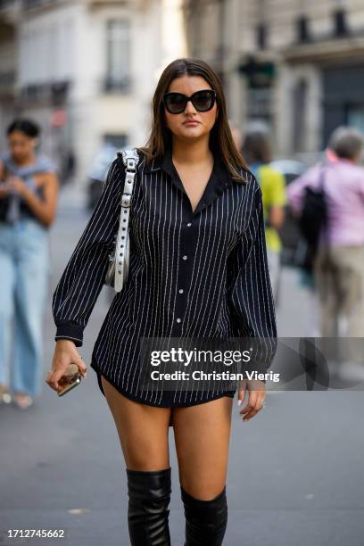 Guest wears black white stripped button shirt, over knees boots, silver bag outside RDNT Andre Tan during the Womenswear Spring/Summer 2024 as part...