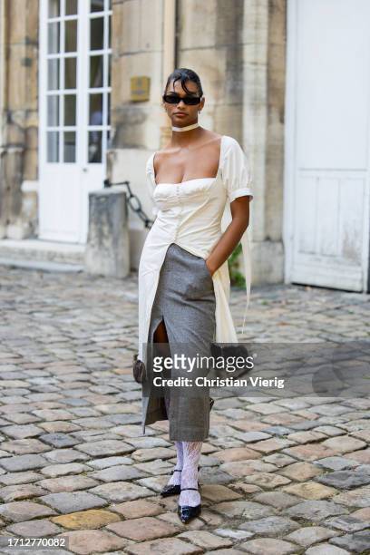 Guest wears white cut out dress, grey skirt outside RDNT Andre Tan during the Womenswear Spring/Summer 2024 as part of Paris Fashion Week on October...