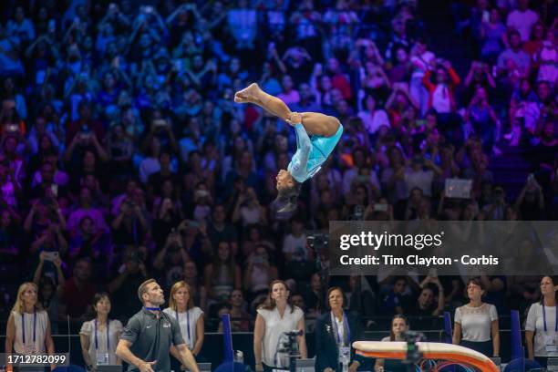 October 01: Simone Biles of the United States performs her Yurchenko double pike vault with coach Laurent Landi on the vault mat for assistance...