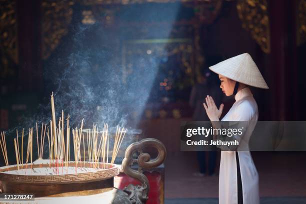 a girl in ao dai praying in a pagoda - ホーチミン ストックフォトと画像