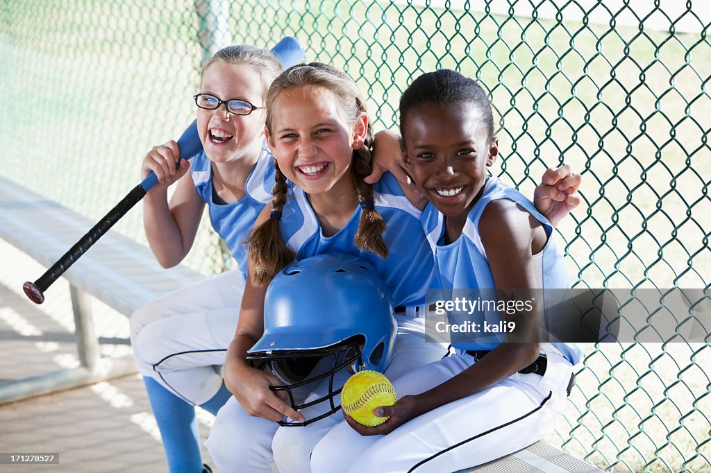 Niñas de softball equipo de estar en el banquillo de campo de béisbol