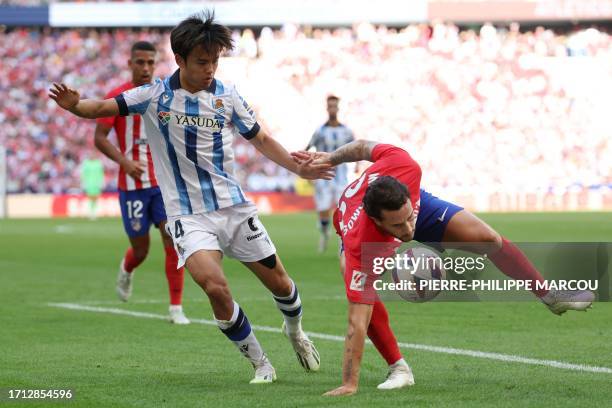 Real Sociedad's Japanese forward Takefusa Kubo vies with Atletico Madrid's Spanish defender Mario Hermoso during the Spanish league football match...