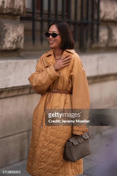 Aimee Song is seen outside Hermes show wearing black sunnies, golden Tiffany hardware collection necklace, camel colored oversized padded coat with...