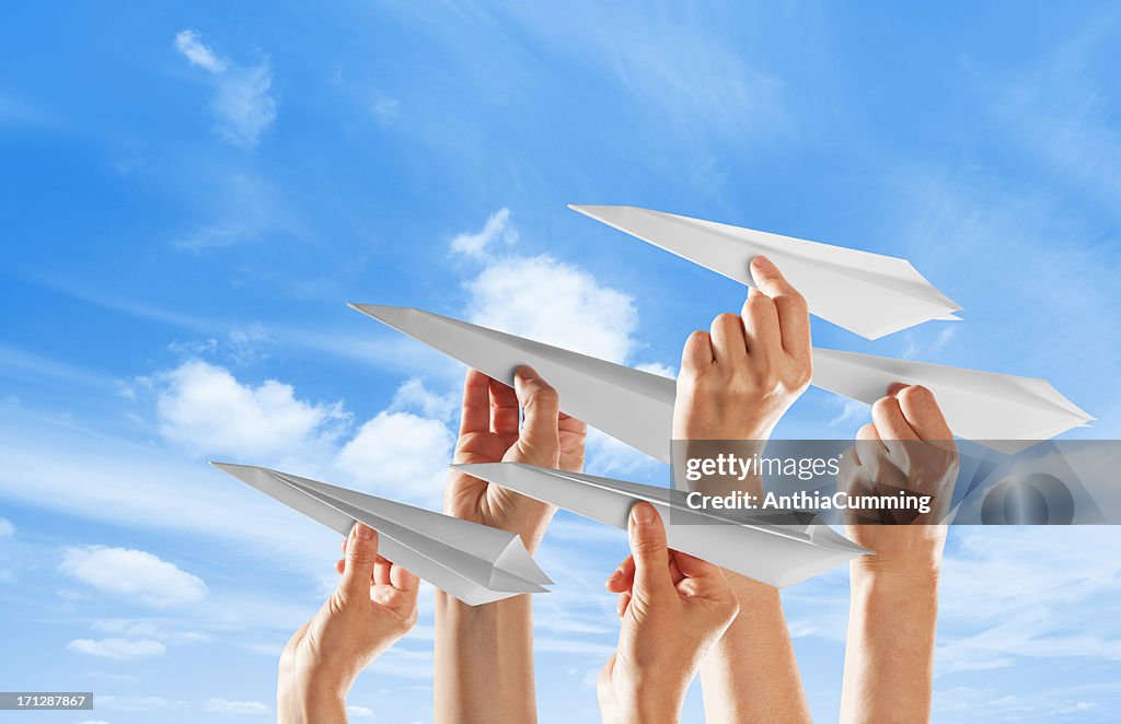 Hände unterschiedlichen Alters machen Papier Flugzeuge auf den Himmel