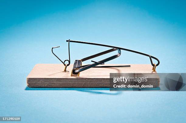 single wooden mousetrap isolated on blue, side view, studio shot - vastzitten stockfoto's en -beelden