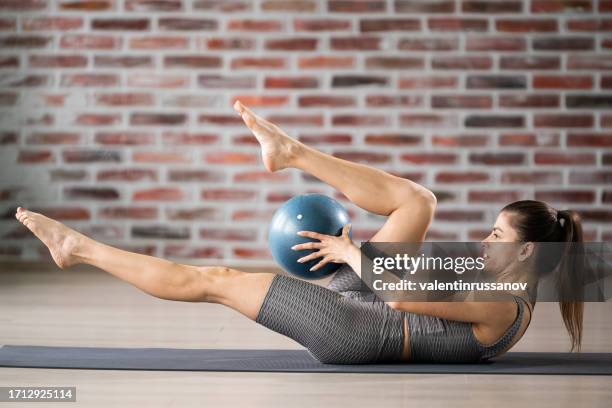 woman exercising pilates using ball at health club - fitness ball imagens e fotografias de stock