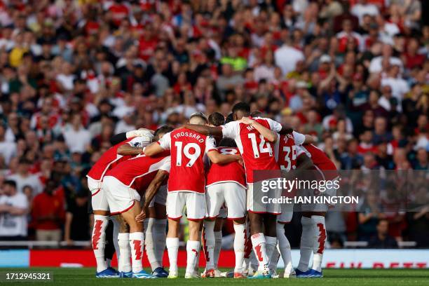 Arsenal players form a group huddle on the pitch ahead of the English Premier League football match between Arsenal and Manchester City at the...