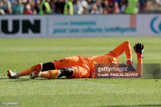 Clermont-Ferrand's French goalkeeper Mory Diaw injured by a firecracker lies on the ground during the French L1 football match between Montpellier...
