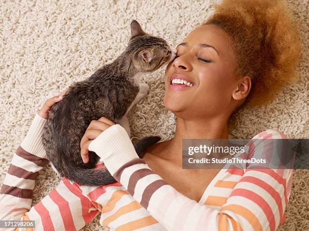 attractive young african woman laying on carpet with cat - cat human face stock pictures, royalty-free photos & images